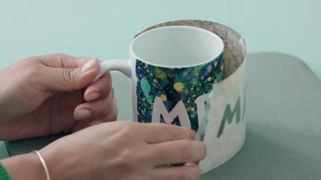 Hand preparing materials to make a mug design.