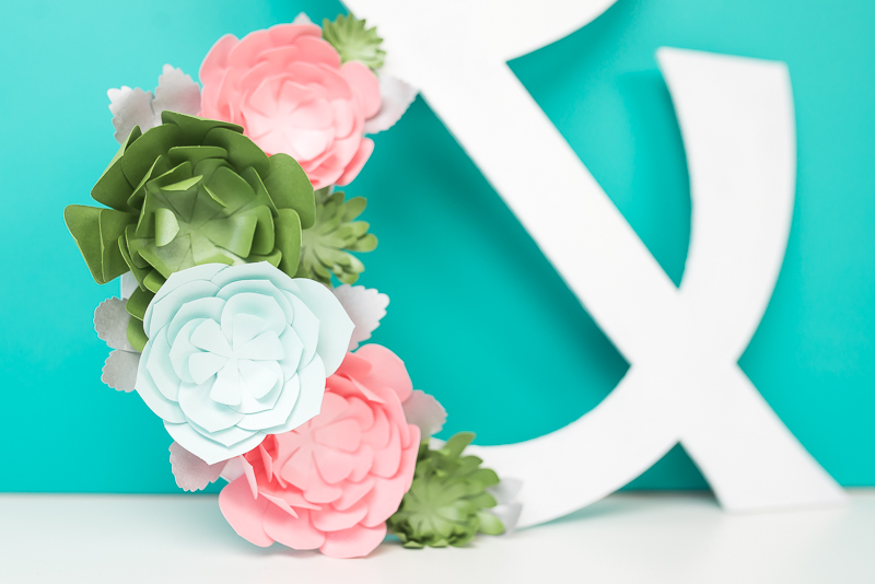 Partial image of a white ampersand decorated with colored paper succulents