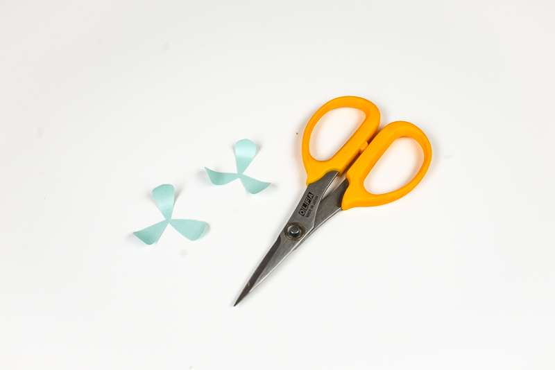 A scissors and images of two layers of an aqua colored paper succulent with curled ends