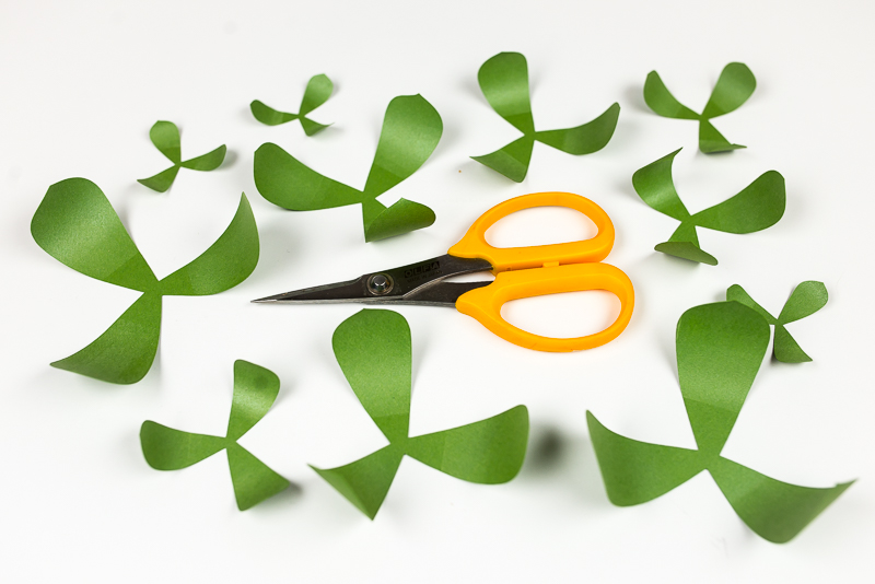 A scissors and images of several layers of a green paper succulent with curled ends